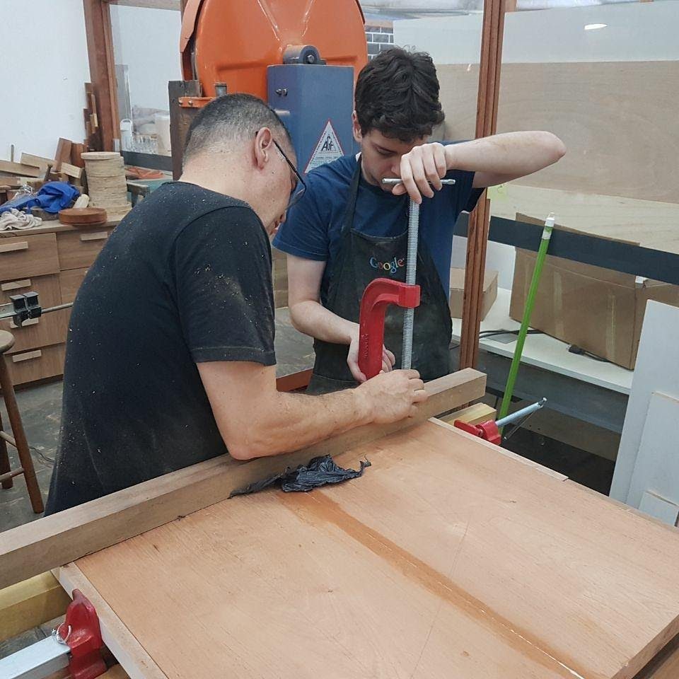 Mauricio e um colega prendendo peças de madeira durante o curso.