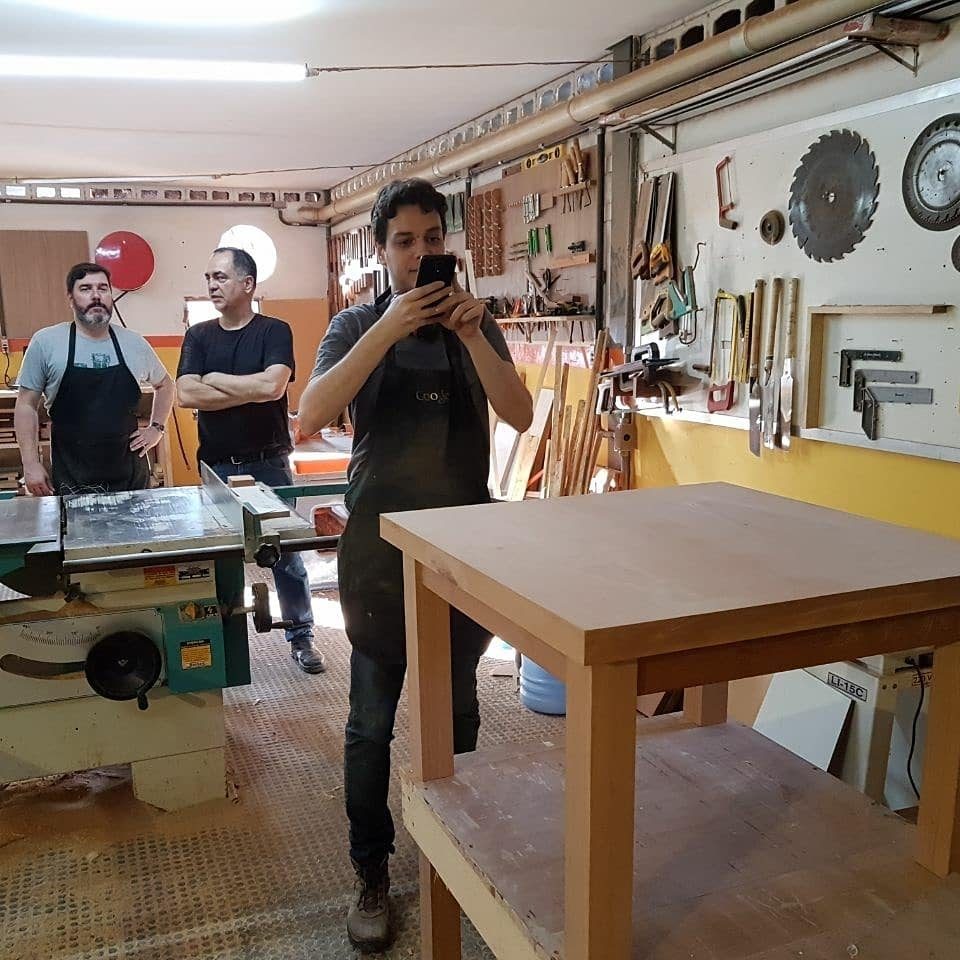 Mauricio fotografando a mesa de centro concluída no curso de marcenaria fina.