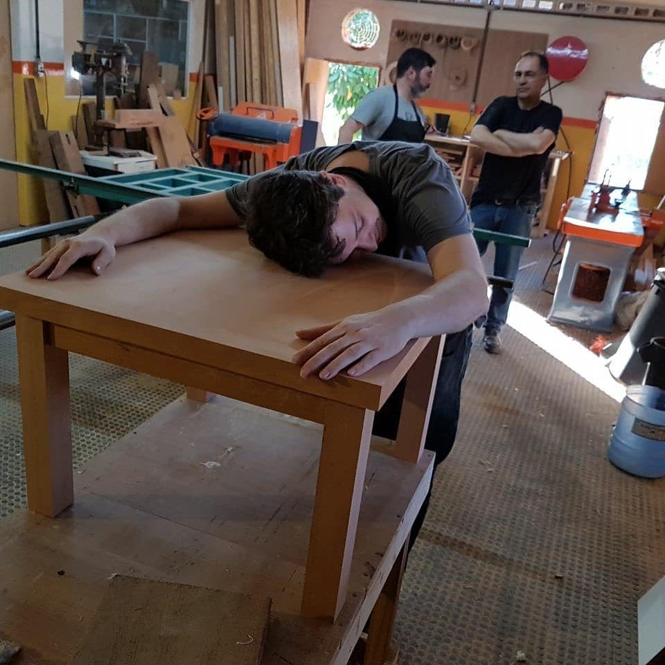 Mauricio abraçando com bom humor a mesa de centro que construiu.