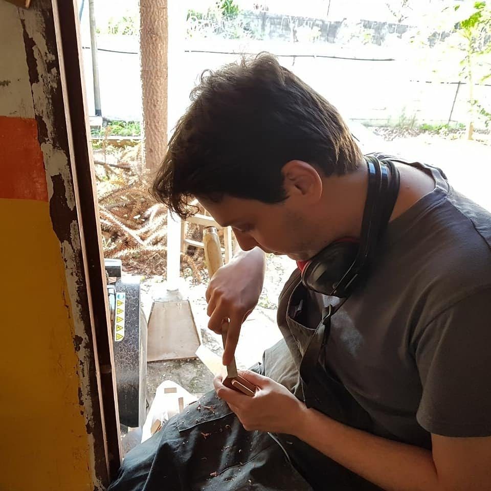 Mauricio trabalhando a madeira com uma ferramenta manual durante o curso de marcenaria fina.