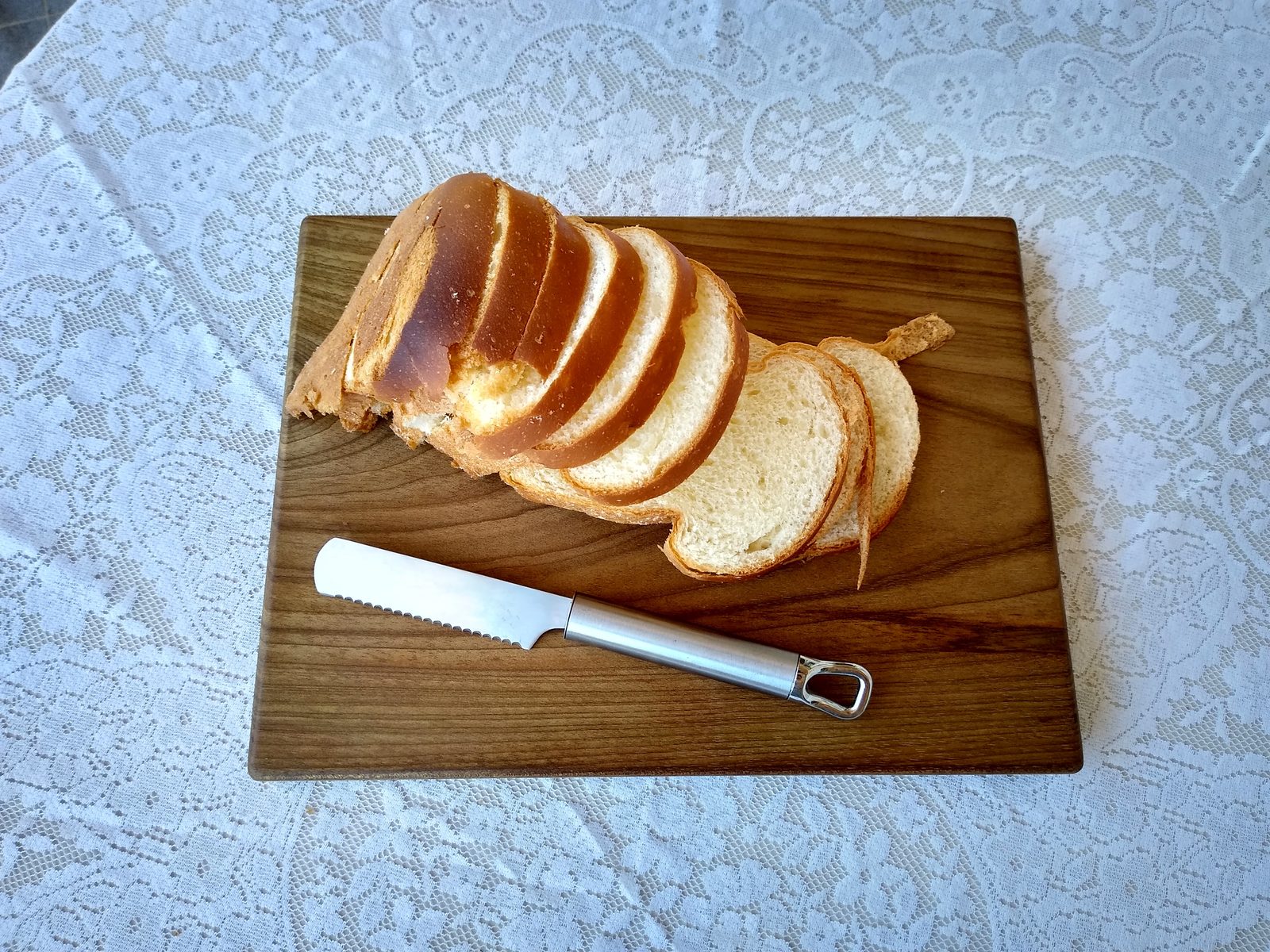 Pão fatiado sobre uma tábua artesanal de madeira.