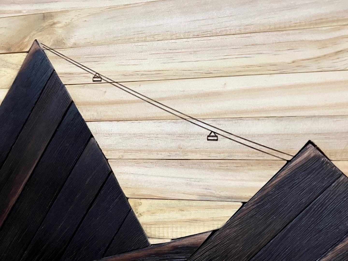 Detalhe do relevo, dos veios da madeira e do teleférico gravado no quadro.