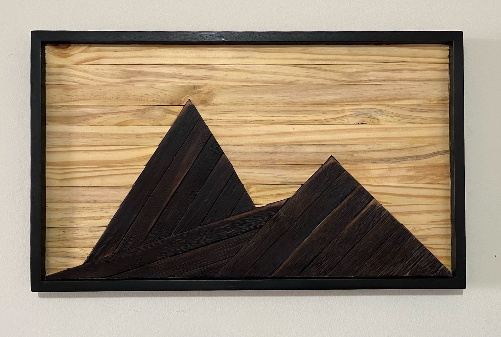 Quadro autoral em madeira representando uma paisagem de montanhas.