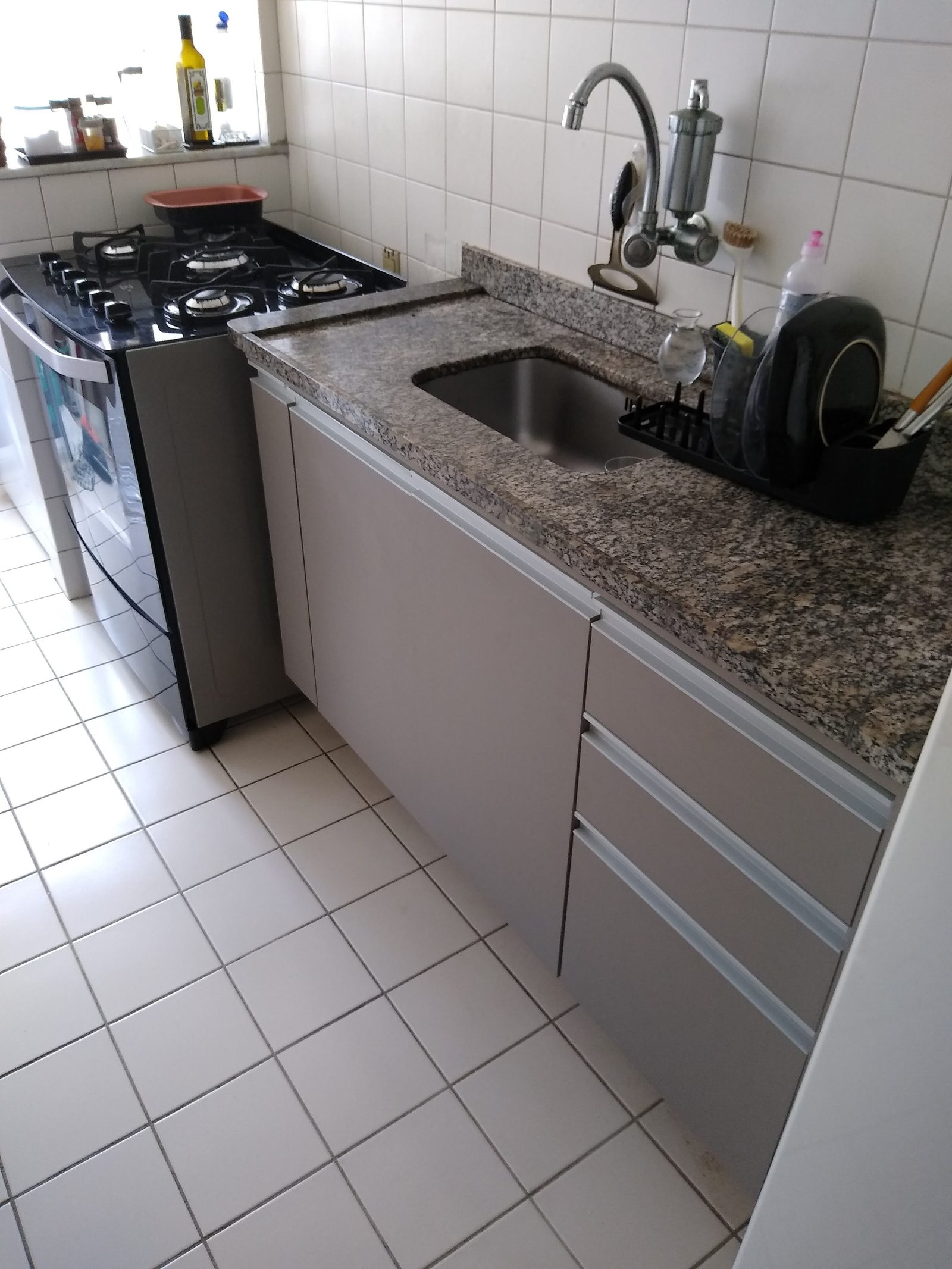 Armários inferiores cinza-claro feitos sob medida para uma cozinha compacta.