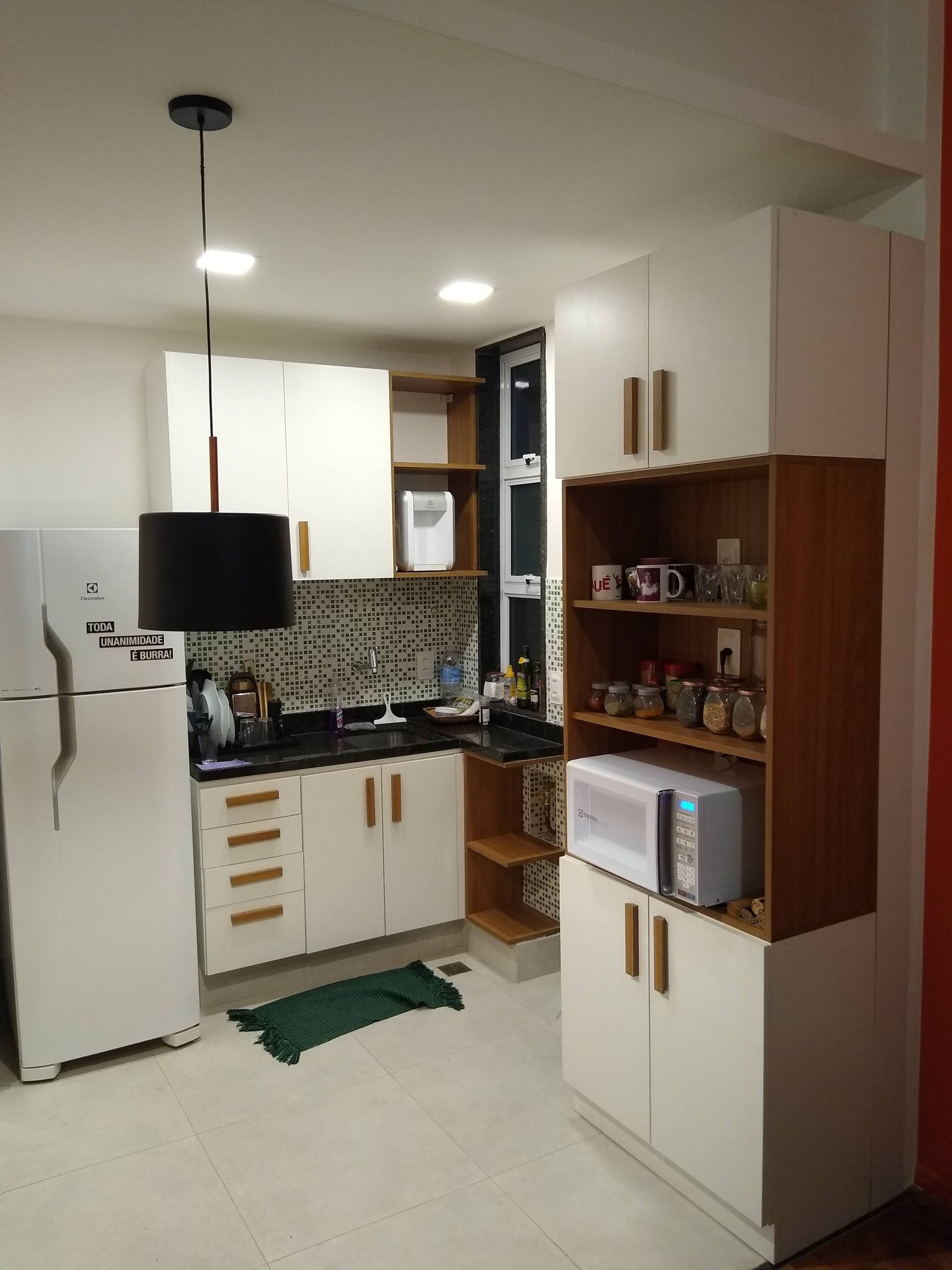 Cozinha sob medida com marcenaria branca, puxadores e nichos em madeira.