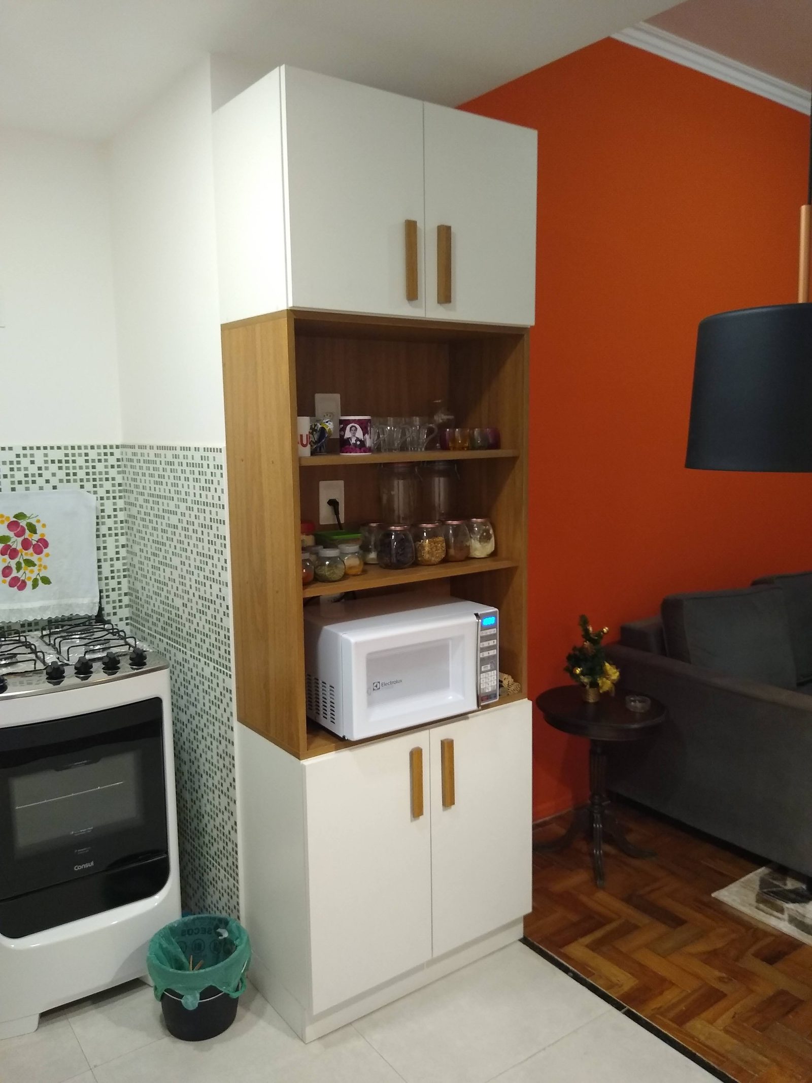 Torre de cozinha com armários brancos, nichos de madeira e espaço para micro-ondas.