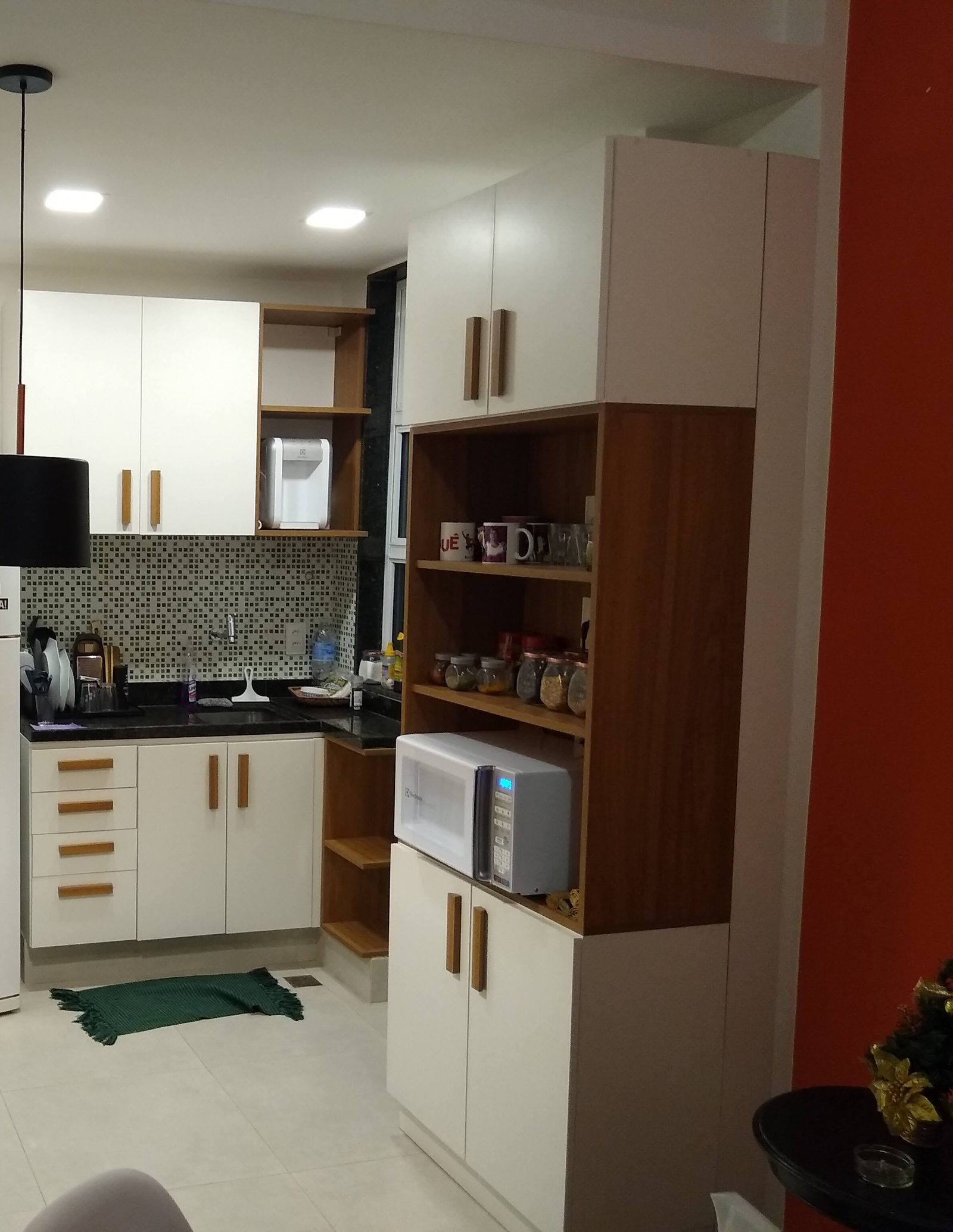 Cozinha compacta com marcenaria branca, puxadores e nichos em madeira.