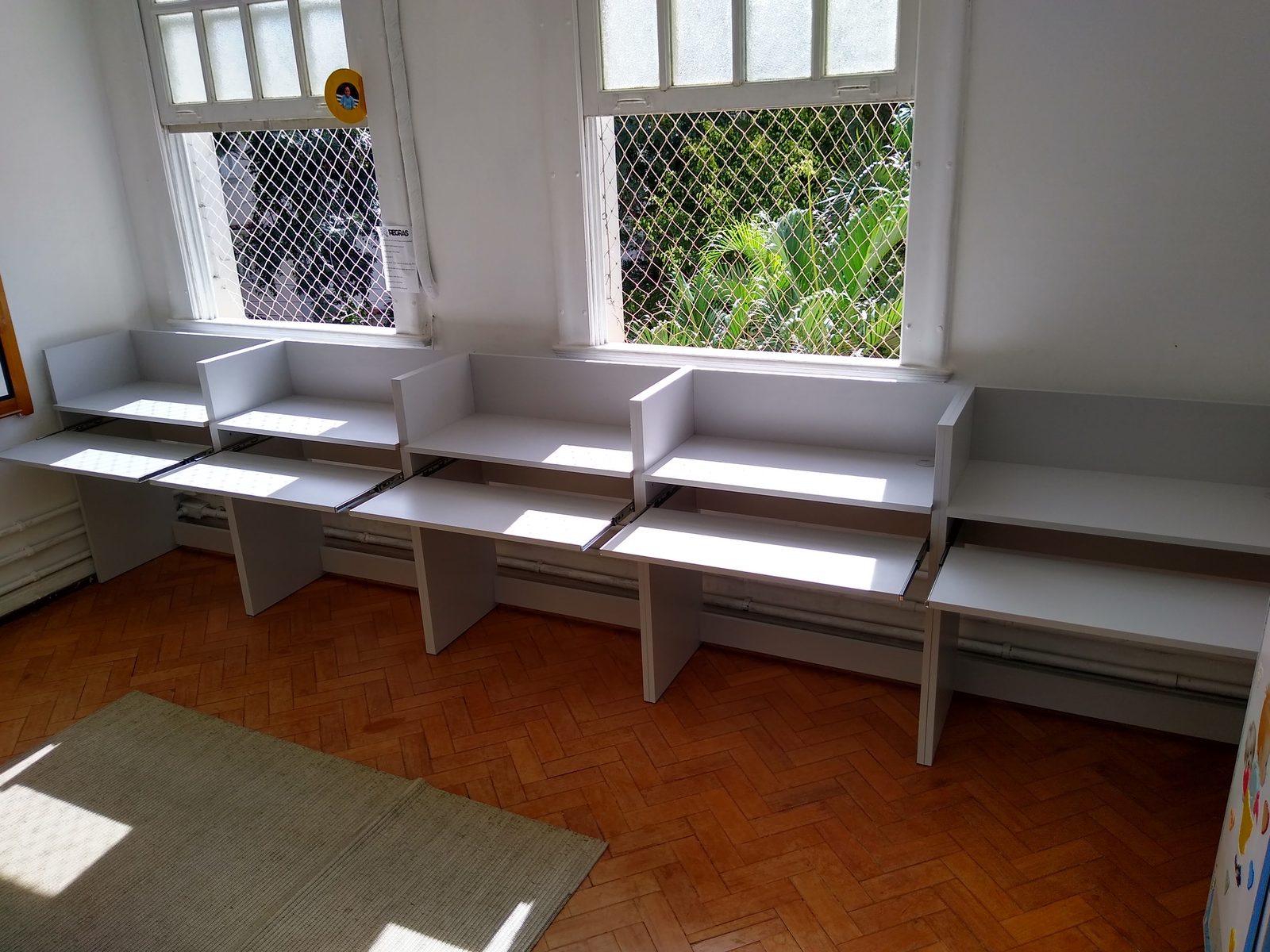 Estação modular branca com superfícies retráteis abertas sob as janelas.